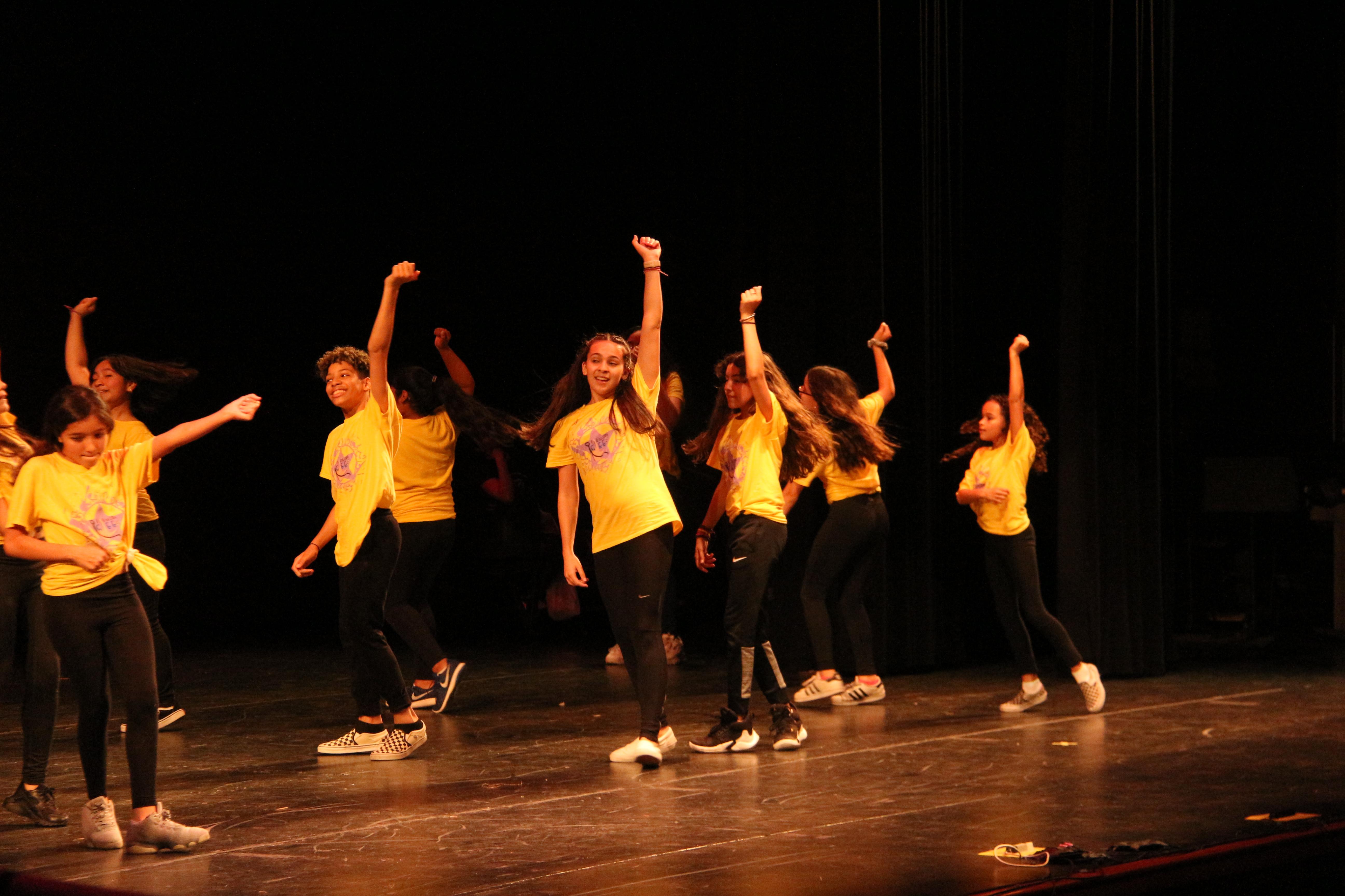 middle school girls wearing yellow t-shirts dancing together